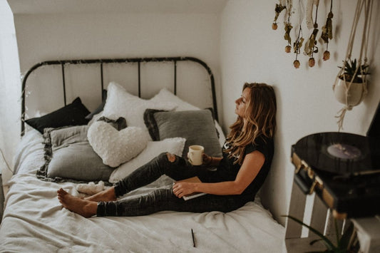 woman sat on bed drinking tea for cramps