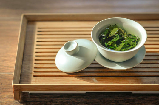green tea leaves in white cup on wooden tray